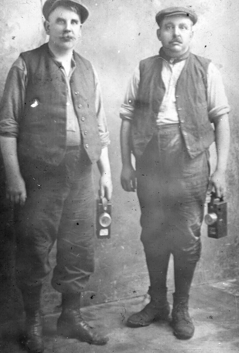 Two middle aged miners with their lamps, at a colliery in South Wales_Mary Evans Roger Worsley Archive.jpg