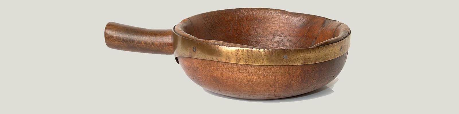 A wooden bowl with brass around the edges, designed to hold coins for weighing