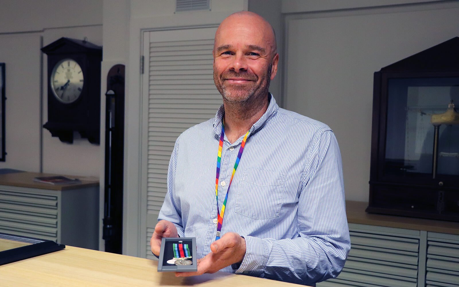 Richard Phelps standing behind a desk holding a medal