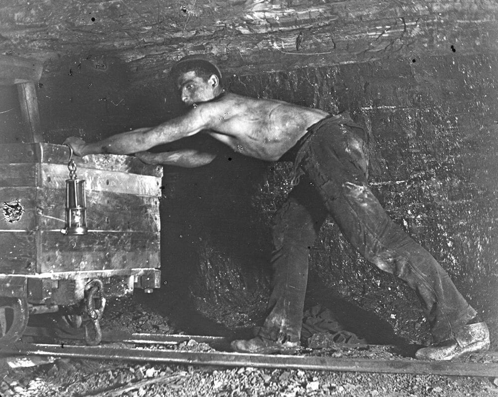Welsh miner in coal mine pushing truck_Mary Evans  Roger Worsley Archive.jpg