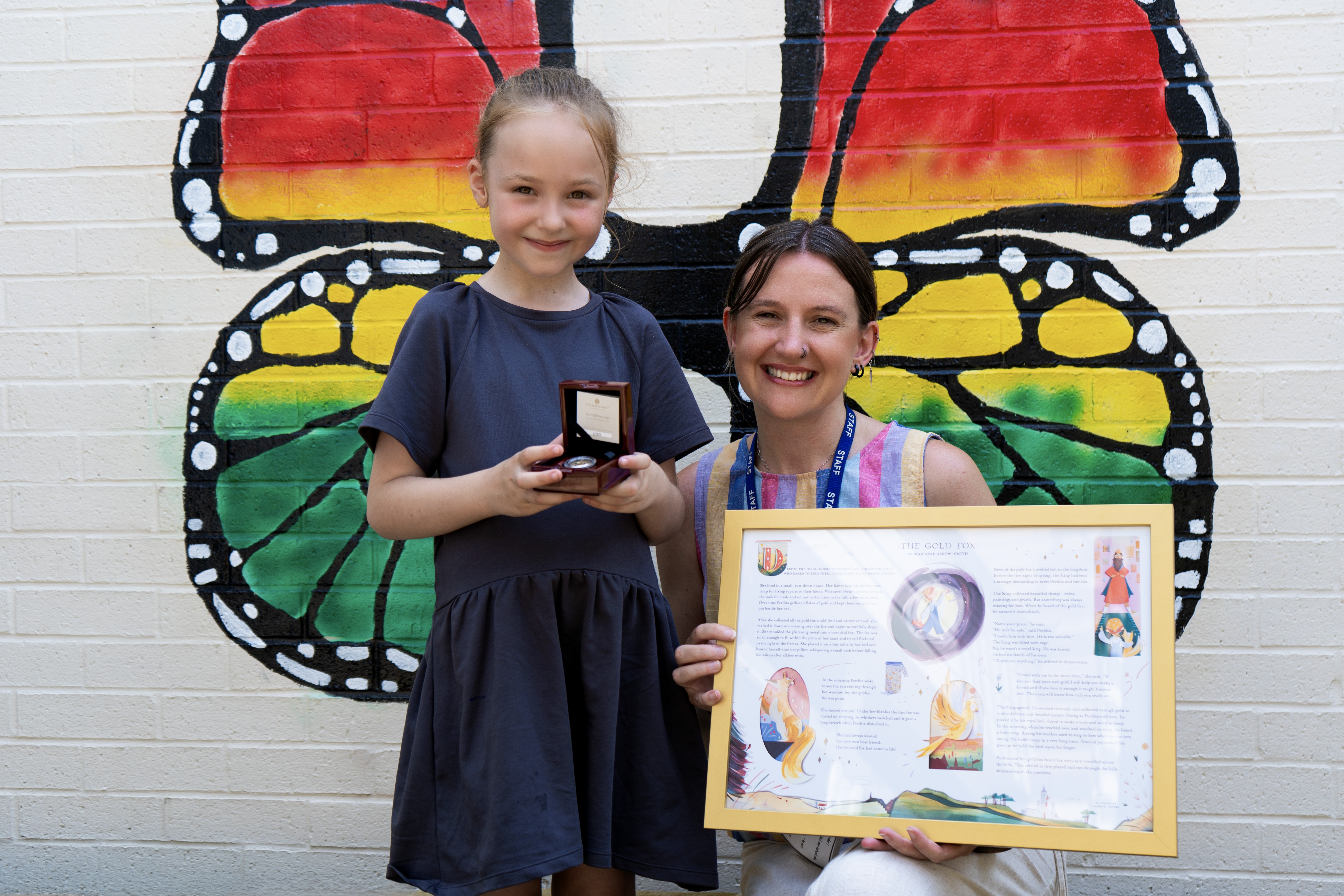 Marlowe and her teacher holding her coin and framed story