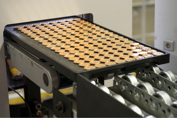Coin production. Rows of gold coins on a machine 