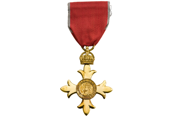 A photograph of an OBE medal. The medal is gold and has a red ribbon with vertical grey stripes on both the edges.