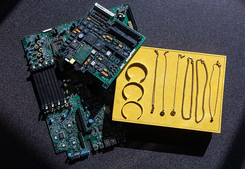A group of circuit boards next to jewellery made from gold recycled from circuit boards