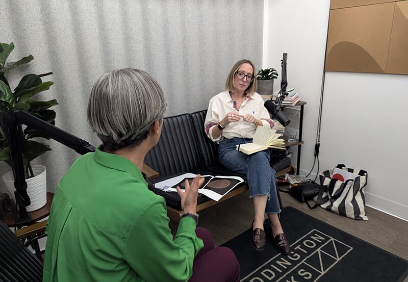 A woman sat at a work bench making small gold jump rings for jewellery