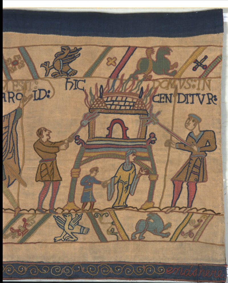 An image of the replica Bayeux Tapestry at Reading Museum this scene shows the Normans landing in England and setting fire to a house while a woman and child flee