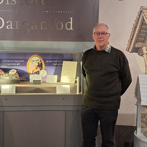 Bob Meggs standing in front of the exhibition case containing his mother's Maundy memorabilia