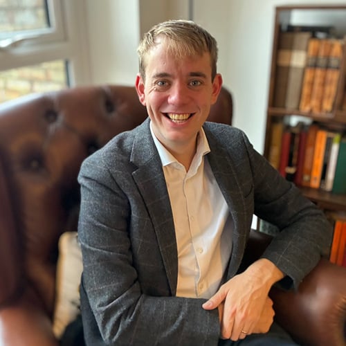 Image of Dr Daniel Rignall sitting in a library