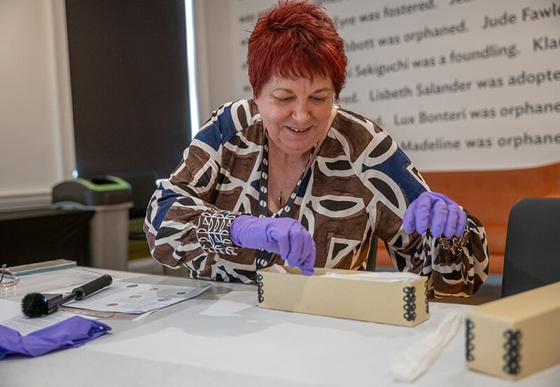 A man at a work bench with lots of tools making delicate gold jewellery