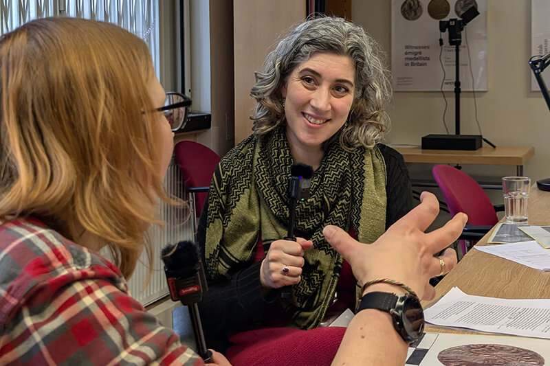 Amal Khreisheh and Susan Sandford sat by a wooden table talking into microphones