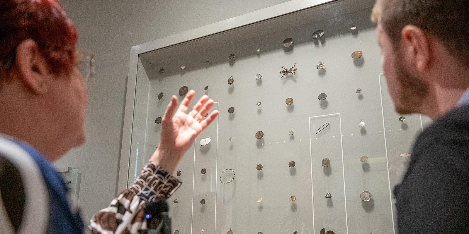 David Mason looking up at an exhibition case full of tokens at the Foundling Museum